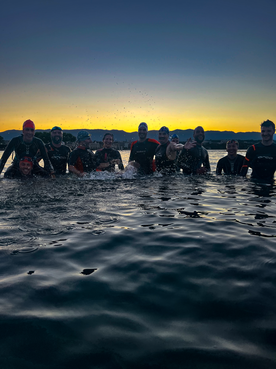 Silhouettes de triathlètes entrant dans l'eau au coucher du soleil